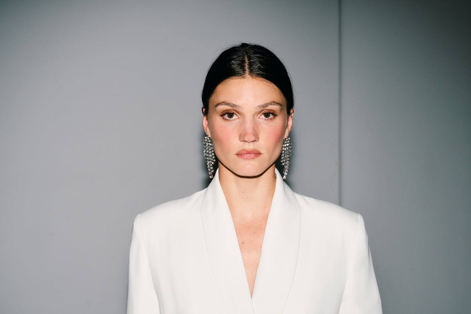 Woman wearing a white blazer against a gray background