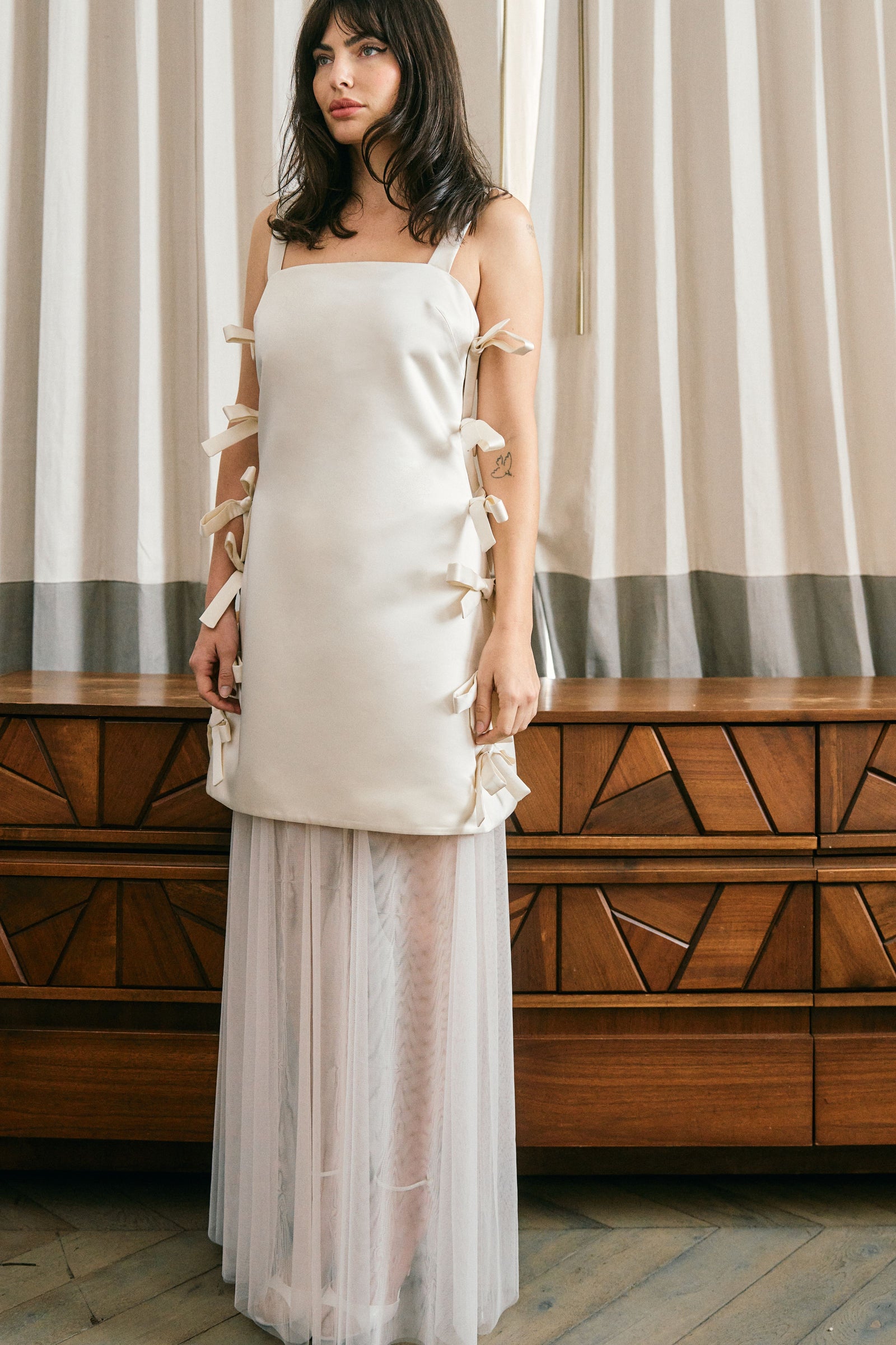 woman standing up straight in white wedding dress with ties up and down both sides