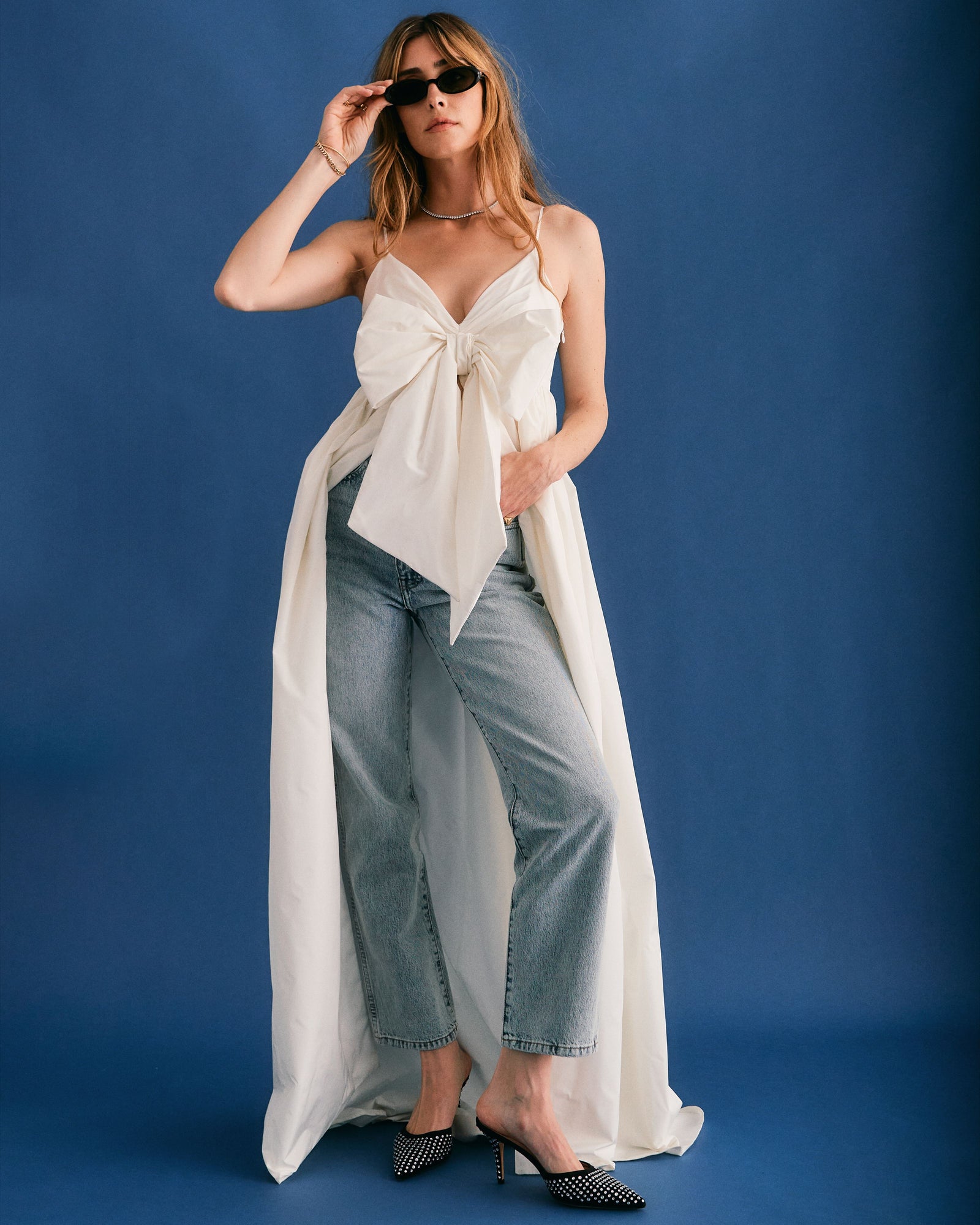 woman in white wedding dress with big bow on front in jeans